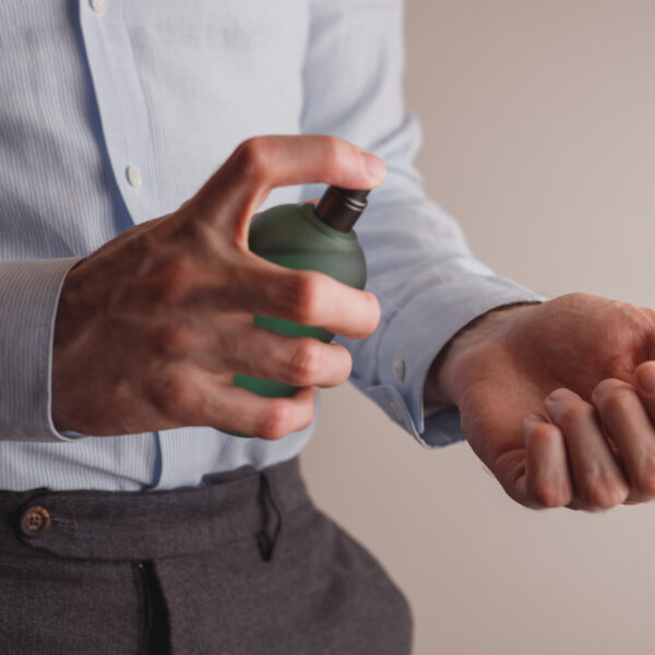 Man in formal wear holding perfume bottle, closeup. Space for text